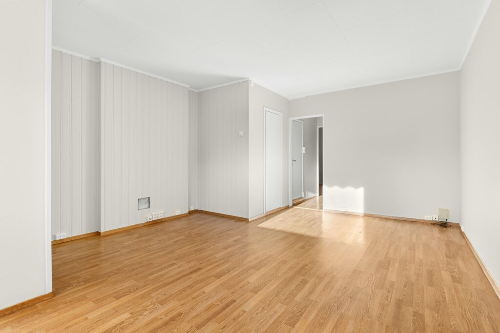 An empty room with hard wood floors and white walls
